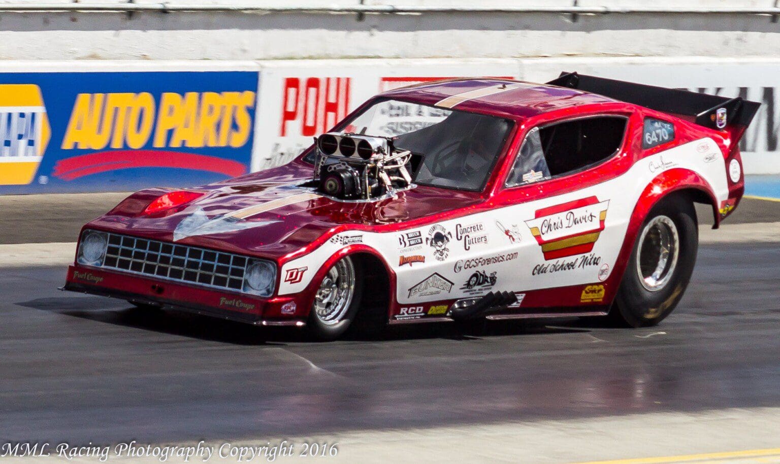 A drag racing car with a supercharged engine on the track.