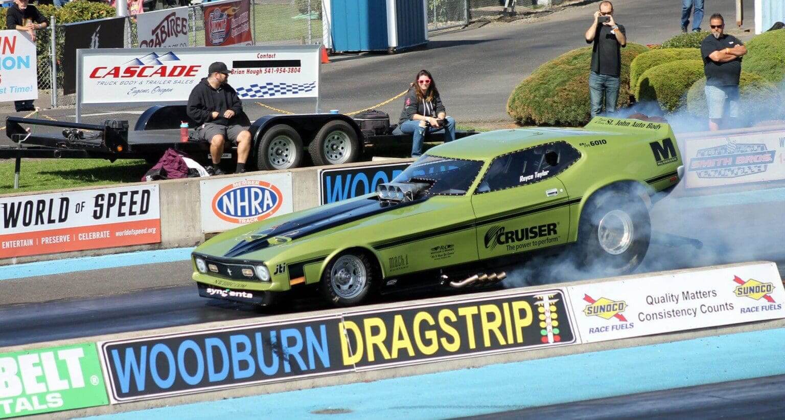 A green drag racing car speeding down Woodburn Dragstrip.