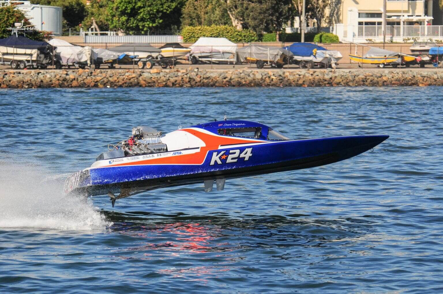 A blue and red powerboat labeled K24 speeding on water.
