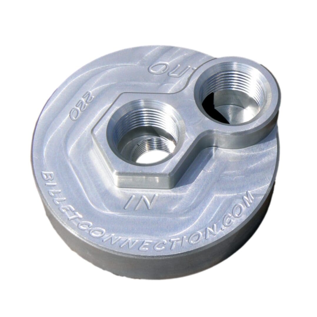 A metallic, round mechanical part with two holes and engraved text.