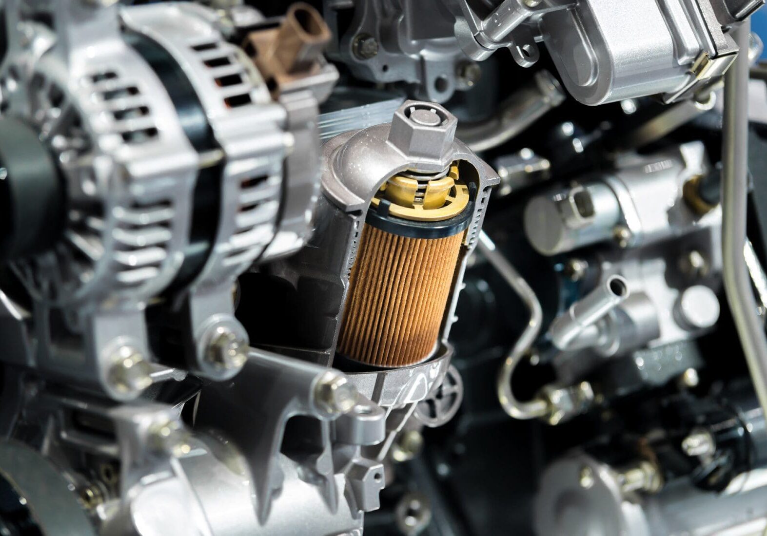 Close-up of a car engine with a visible oil filter and various components, including an alternator and metallic parts.